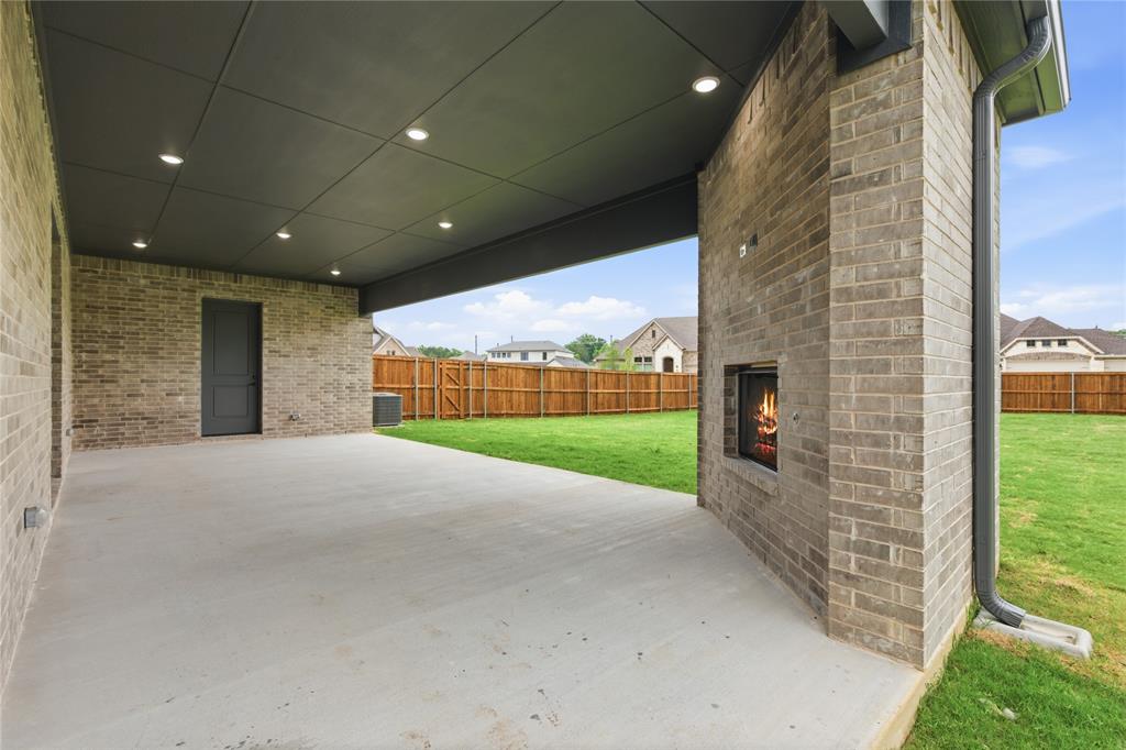 702 Anne Road Van Alstyne, TX 75495 - Photo 24 of 27 Expansive covered patio featuring a brick exterior with an outdoor fireplace, recessed lighting, and a grey plank ceiling