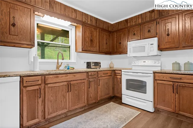 a kitchen with granite countertop wooden cabinets stainless steel appliances and a sink
