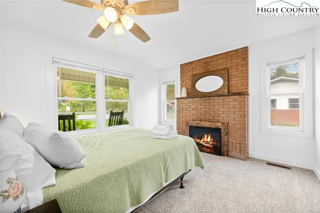 a bed sitting in a bedroom next to a window with a fireplace and a chandelier