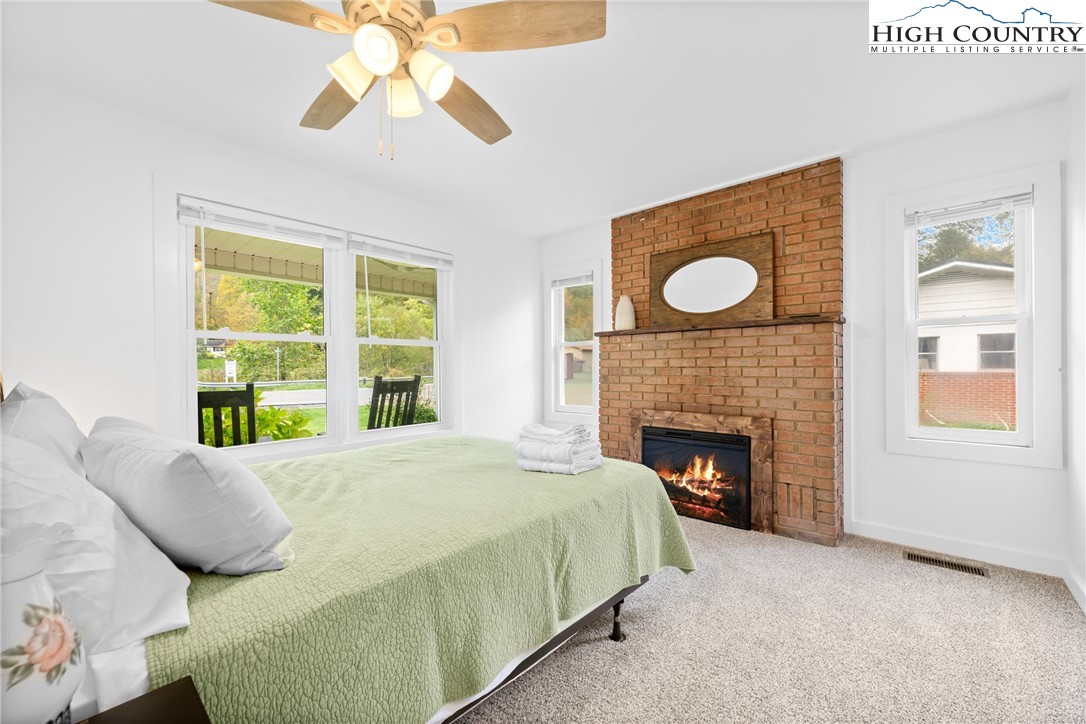 1044 Highway 321 Vilas, NC 28692 - Photo 22 of 47 a bed sitting in a bedroom next to a window with a fireplace and a chandelier