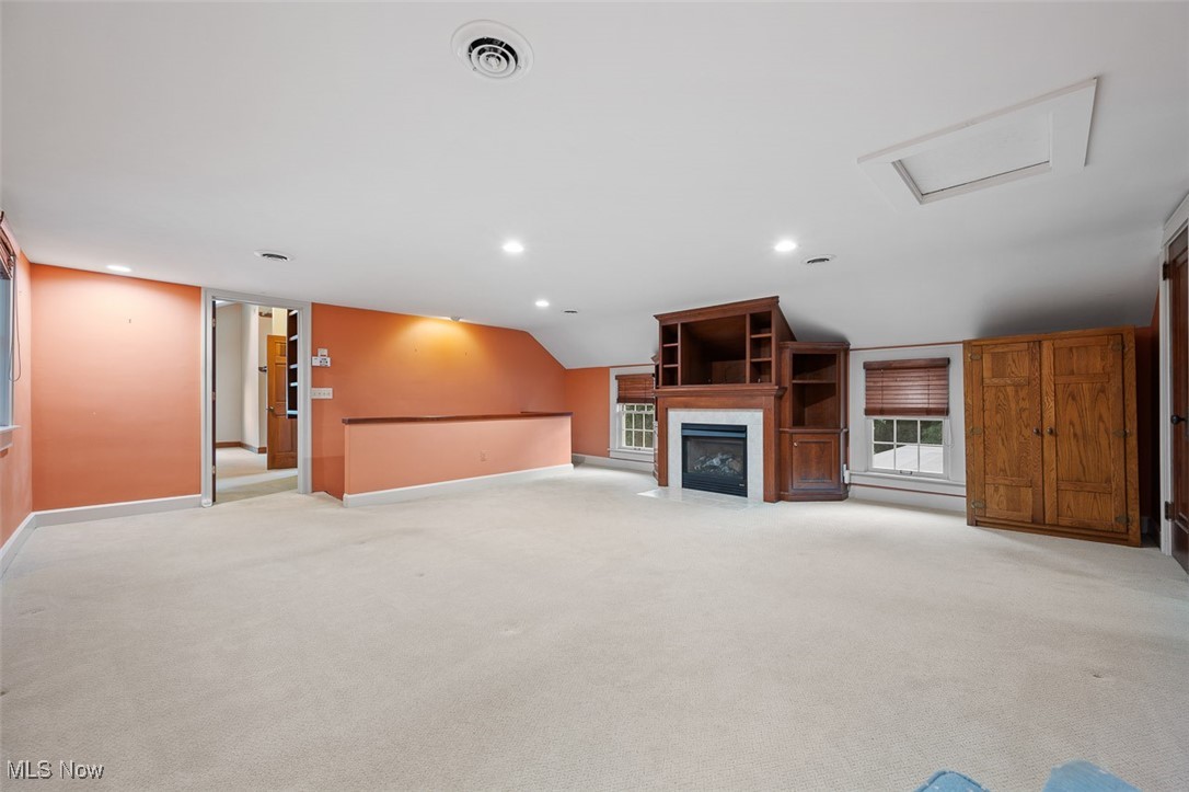 256 Everhard Road Southwest North Canton, OH 44709 - Photo 16 of 45 Unfurnished living room with attic access, a fireplace with flush hearth, recessed lighting, light colored carpet, and lofted ceiling