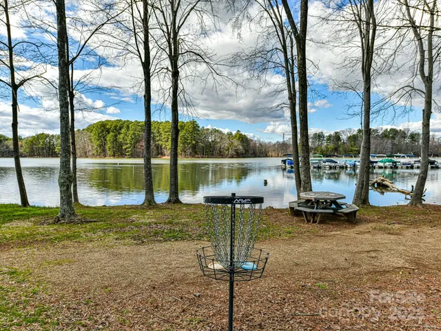 a view of a lake with a sitting space and large trees