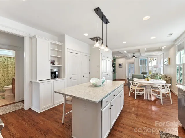 a open kitchen with stainless steel appliances granite countertop a table chairs and a refrigerator