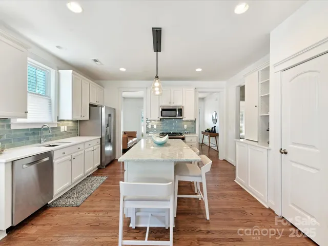 a large kitchen with granite countertop lots of counter space dining table and stainless steel appliances
