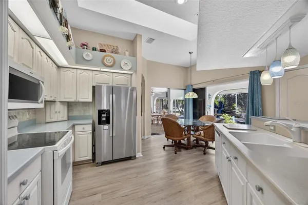 a kitchen with stainless steel appliances granite countertop a refrigerator a sink dishwasher a dining table and chairs with wooden floor