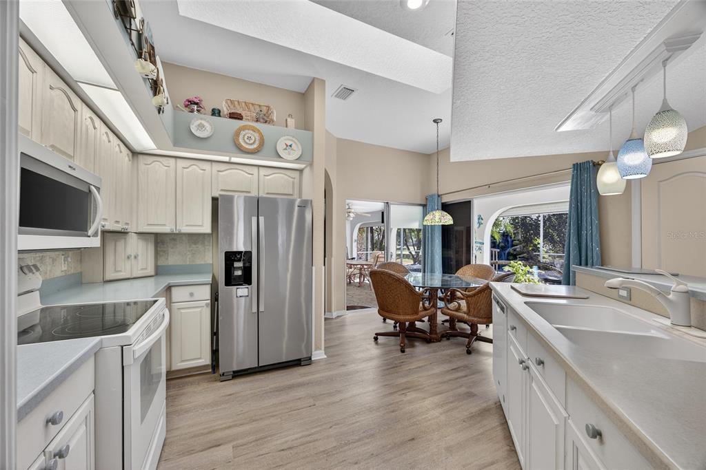 1421 Rio De Janeiro Avenue Punta Gorda, FL 33983 - Photo 8 of 34 a kitchen with stainless steel appliances granite countertop a refrigerator a sink dishwasher a dining table and chairs with wooden floor