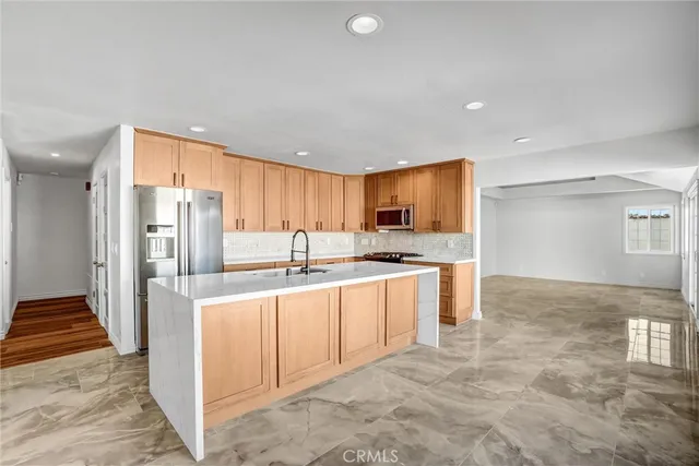 a large kitchen with stainless steel appliances kitchen island granite countertop a refrigerator and a sink
