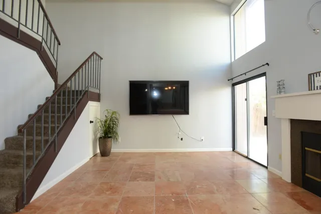 a view of an empty room with wooden floor and a fireplace