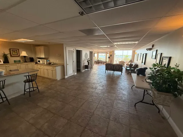 a open kitchen with stainless steel appliances kitchen island granite countertop a table chairs and a refrigerator