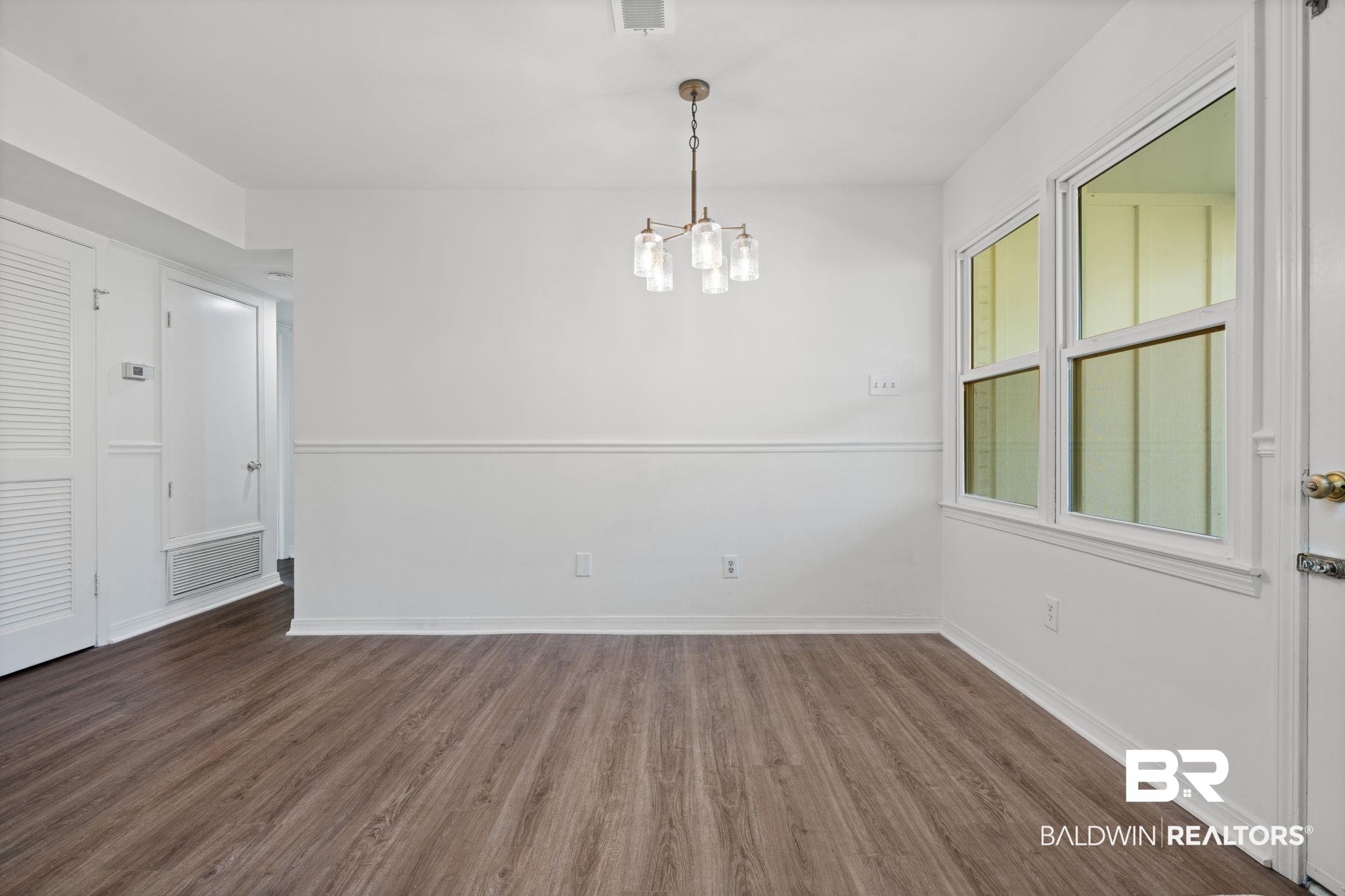 511 Wacker Lane North Mobile, AL 36608 - Photo 23 of 45 Empty room with a chandelier and dark wood-style floors