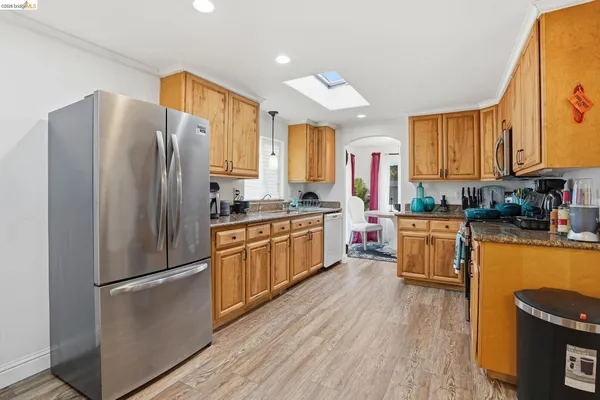 a kitchen with granite countertop stainless steel appliances a refrigerator cabinets and wooden floor