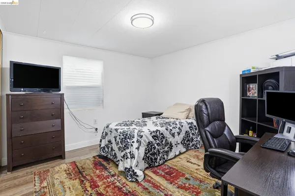a bedroom with bed and a flat tv screen on dresser