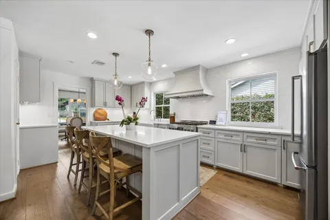 a kitchen with stainless steel appliances a table chairs refrigerator and sink