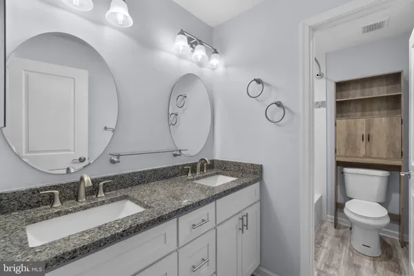 a bathroom with a granite countertop sink a toilet and a mirror