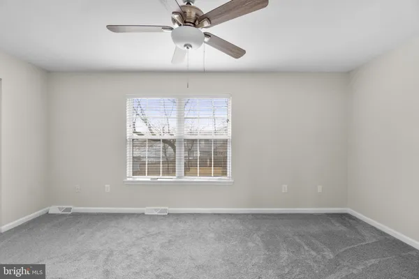 an empty room with a window and a fan