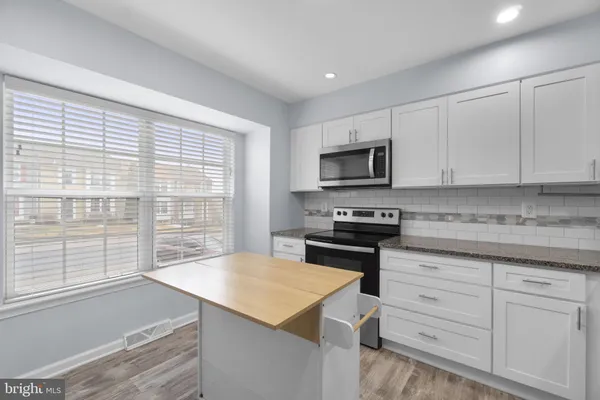 a kitchen with granite countertop a stove a sink and a microwave