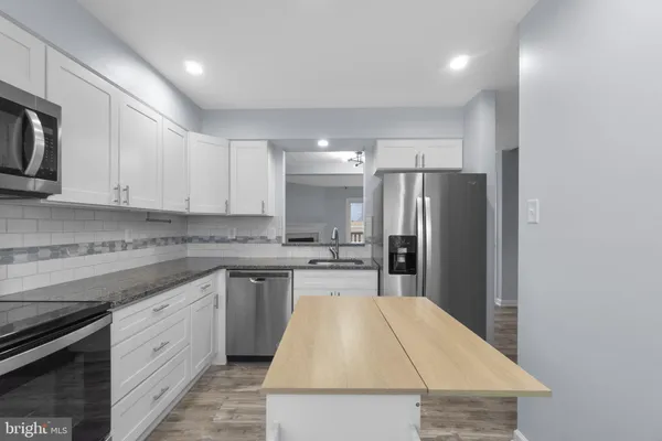 a kitchen with kitchen island a sink stainless steel appliances and cabinets