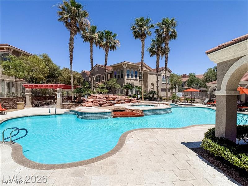 10550 West Alexander Road, Unit 2148 Las Vegas, NV 89129 - Photo 22 of 41 An inviting resort-style pool and spa await, framed by palm trees and architectural beauty.