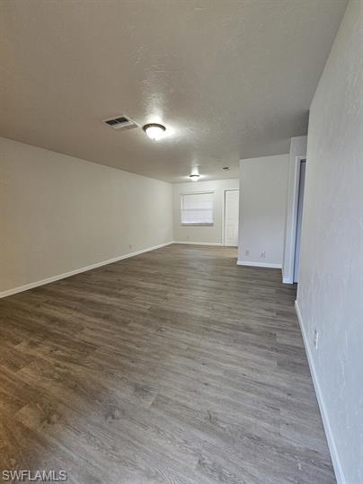 3005 Gordon Street Naples, FL 34112 - Photo 2 of 11 Empty room with dark wood finished floors, a textured ceiling, and a textured wall