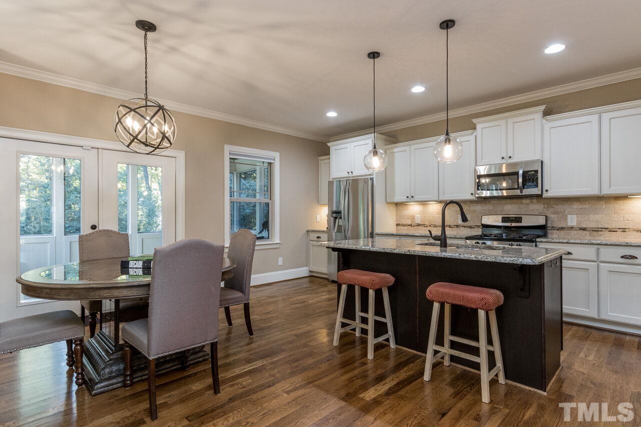 1340 Trinity Road Cary, NC 27513 - Photo 6 of 30 a kitchen with stainless steel appliances granite countertop a stove a refrigerator a kitchen island a table and chairs with wooden floor