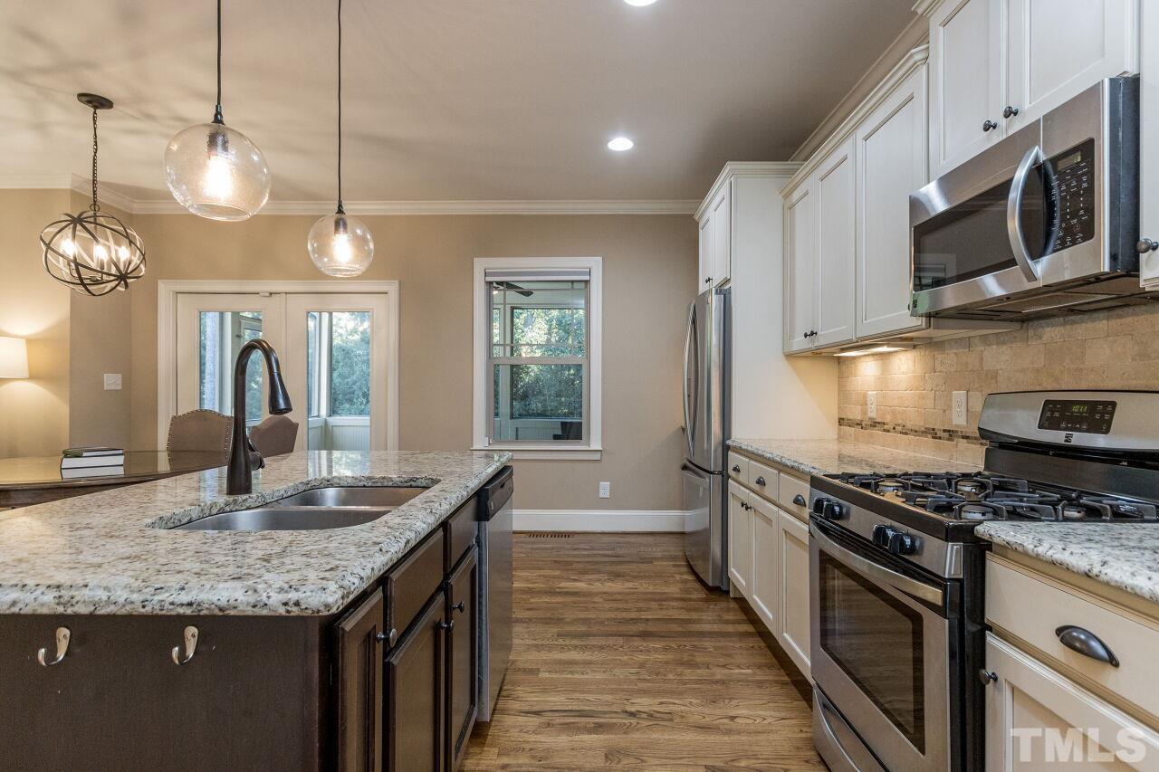 1340 Trinity Road Cary, NC 27513 - Photo 10 of 30 a kitchen with stainless steel appliances granite countertop a stove top oven a sink dishwasher a dining table and chairs with wooden floor