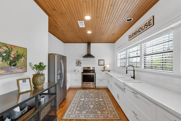 a kitchen with stainless steel appliances a refrigerator a stove a sink dishwasher a dining table and chairs with wooden floor