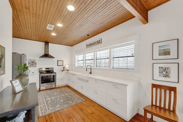 a large kitchen with stainless steel appliances granite countertop a refrigerator a sink dishwasher a stove and white countertops with wooden floor