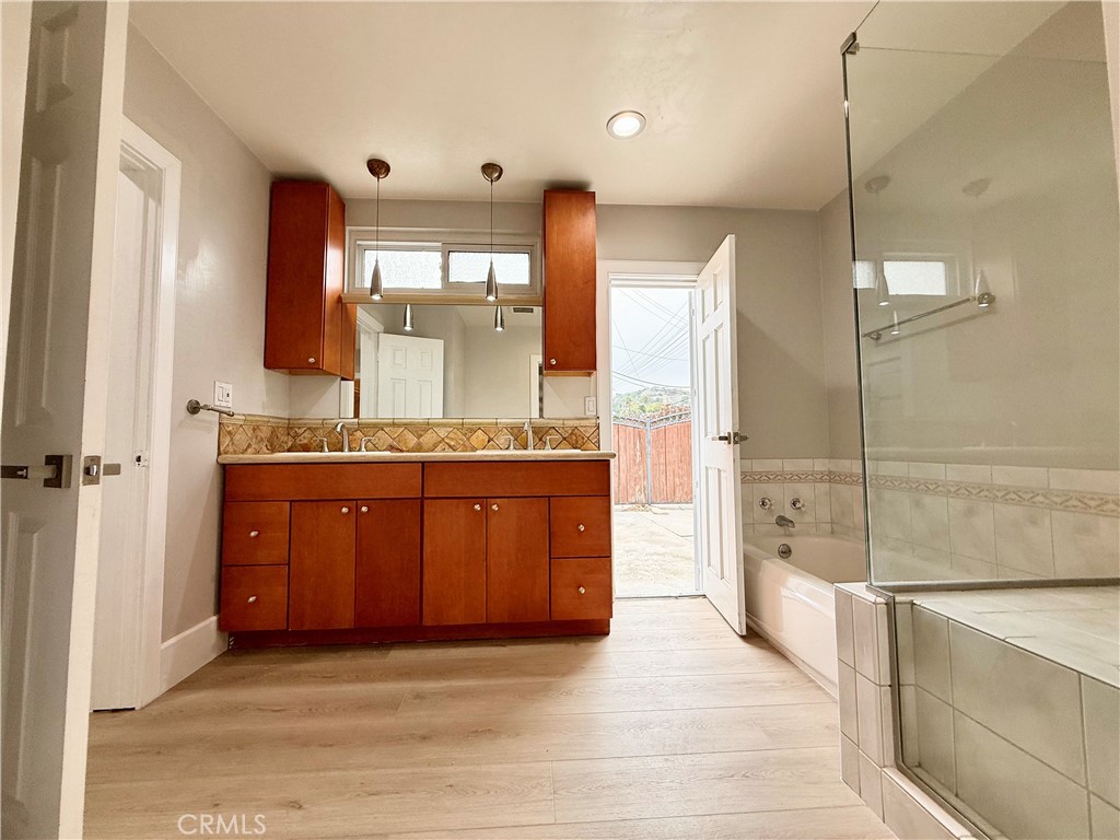 24204 Calvert Street Woodland Hills, CA 91367 - Photo 28 of 70 a bathroom with a granite countertop sink a mirror and a shower
