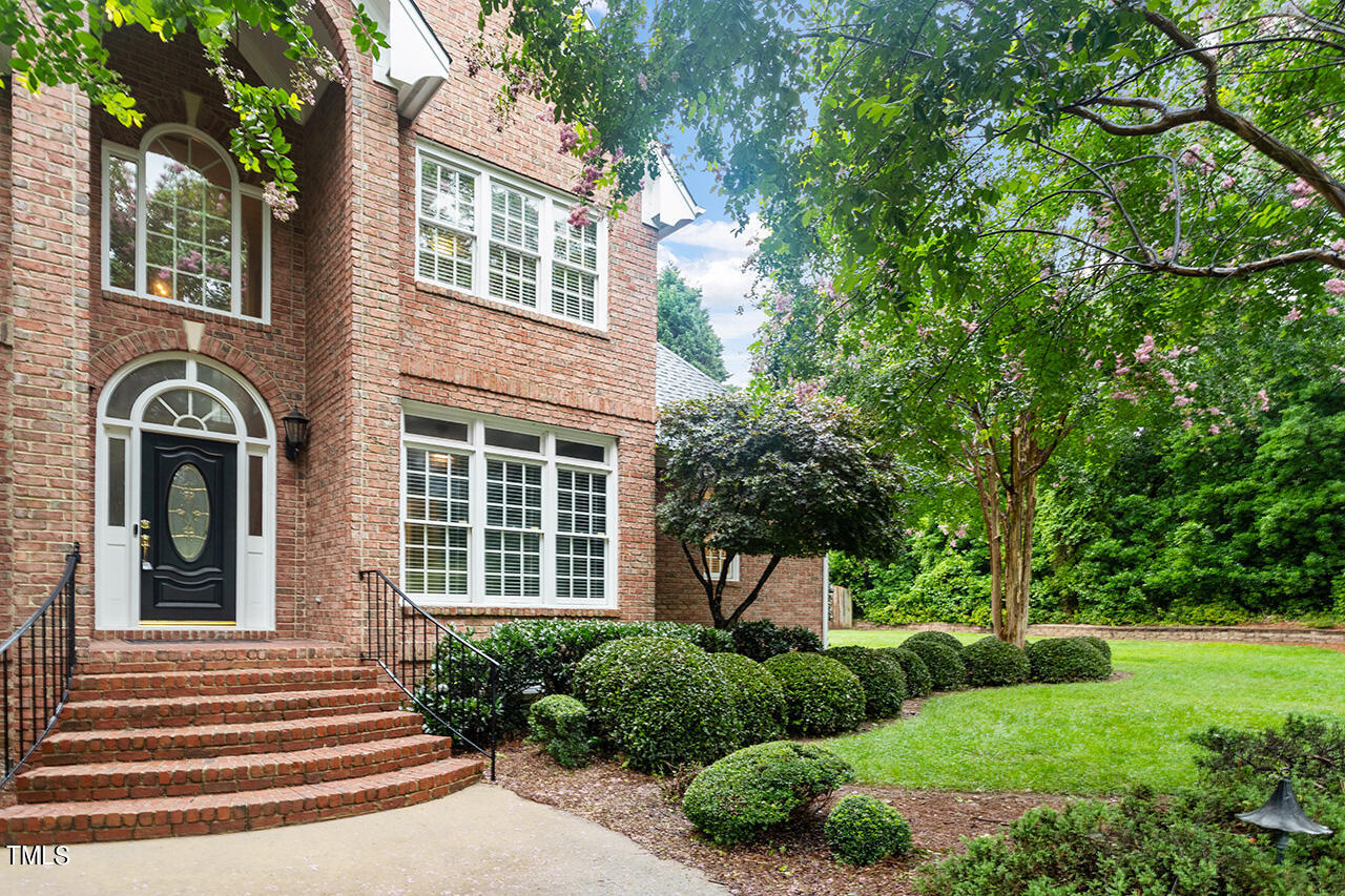909 Rockfall Court Raleigh, NC 27614 - Photo 2 of 38 a view of a house with brick walls and a yard with plants and large trees