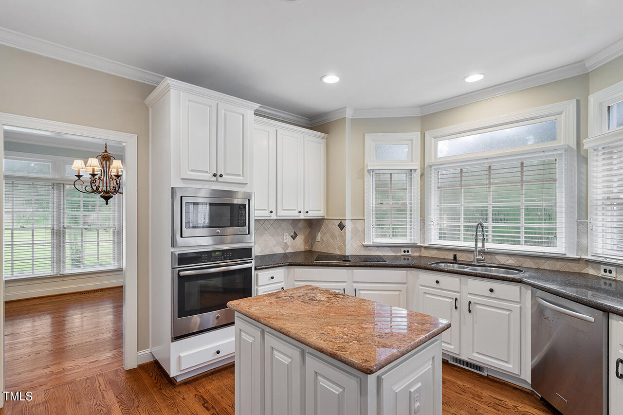 909 Rockfall Court Raleigh, NC 27614 - Photo 9 of 38 a kitchen with granite countertop a sink stove and cabinets