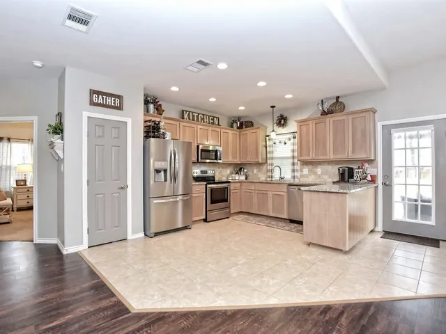 a kitchen with granite countertop a refrigerator and wooden cabinets
