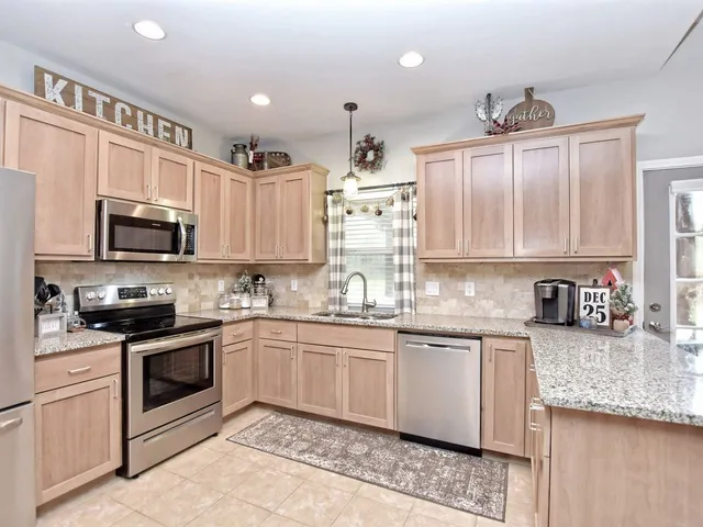 a large kitchen with a large counter top a sink stainless steel appliances and cabinets