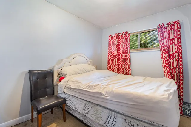 a bedroom with a bed and a dresser next to a window