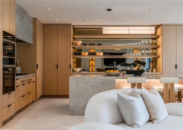 a living room with stainless steel appliances furniture and a kitchen view