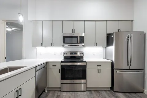 a kitchen with cabinets stainless steel appliances and a counter space