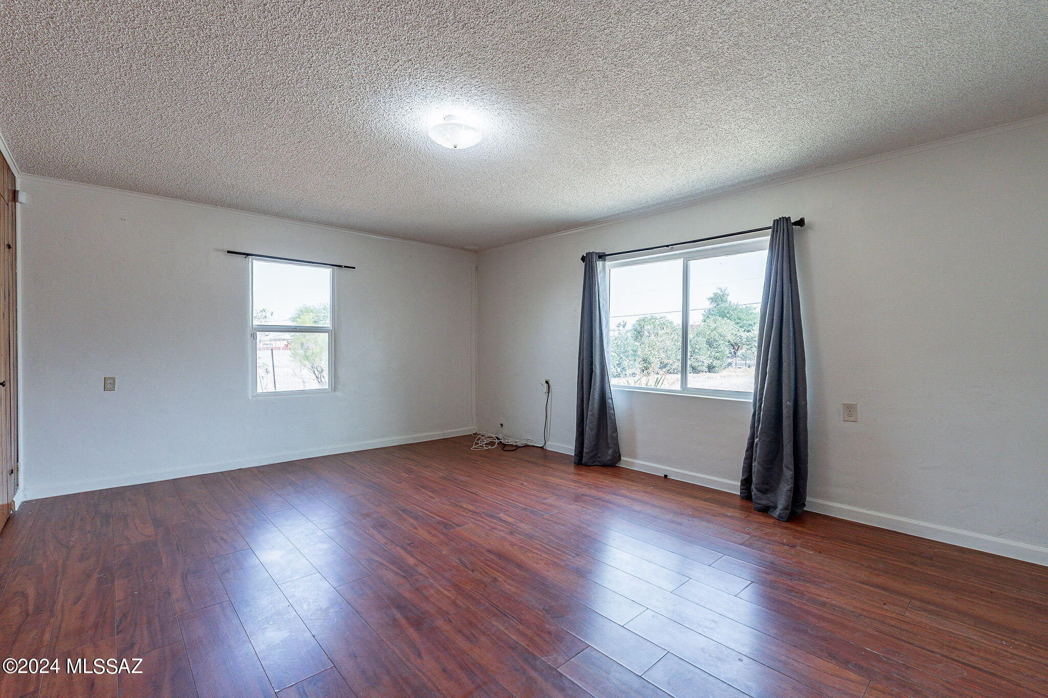 608 East Roger Road Tucson, AZ 85705 - Photo 5 of 13 an empty room with wooden floor and windows