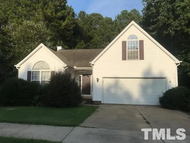 a view of a white house with a small yard and large tree