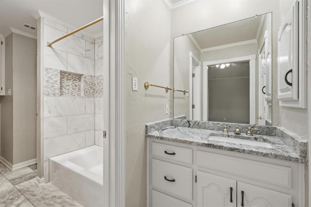 848 Birdsong Bedford, TX 76021 - Photo 27 of 40 a bathroom with a granite countertop sink a mirror a bathtub and shower