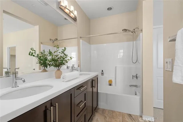 a bathroom with a granite countertop sink a mirror a bathtub and shower