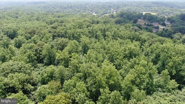 an aerial view of residential house with outdoor space and trees all around