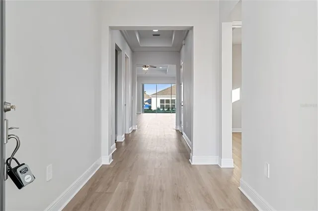 a view of a hallway with wooden floor and a bathroom