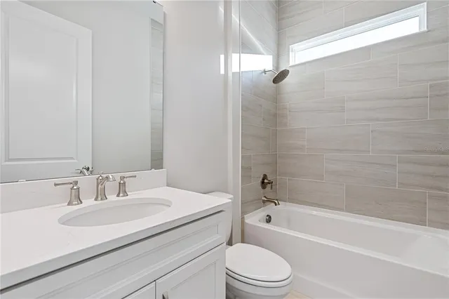 a bathroom with a granite countertop sink a toilet and bathtub