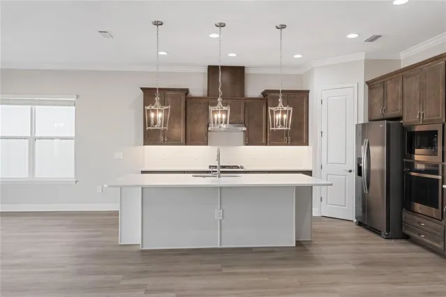 a view of kitchen with center island wooden floor and stainless steel appliances