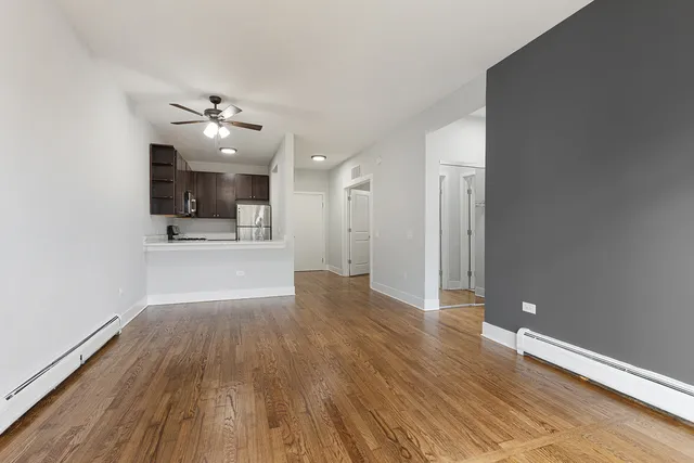 a view of empty room with wooden floor and fan