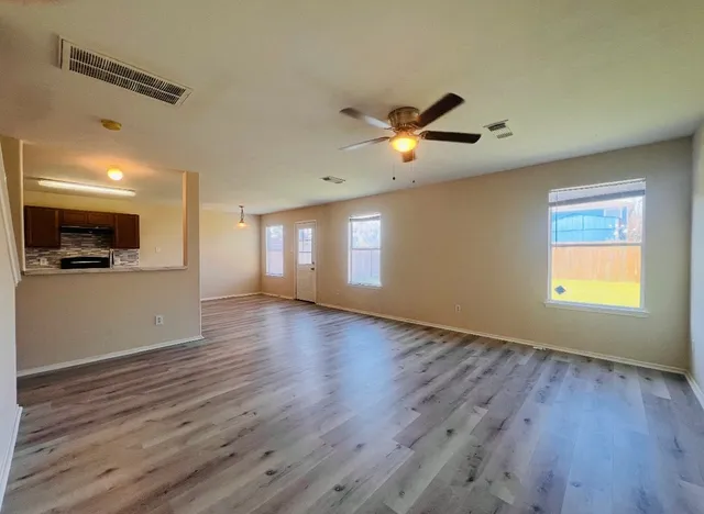 a view of an empty room with a window and wooden floor