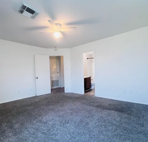 a view of an empty room with a ceiling fan and window