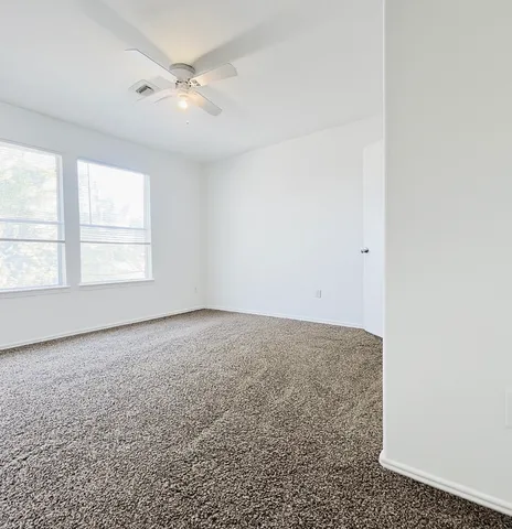an empty room with a window and a ceiling fan