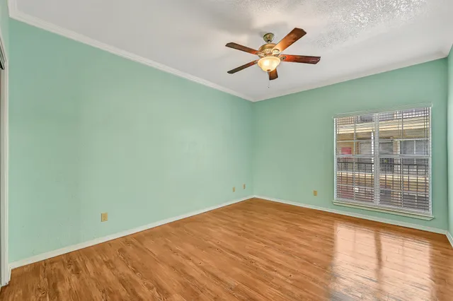 an empty room with ceiling fan and window