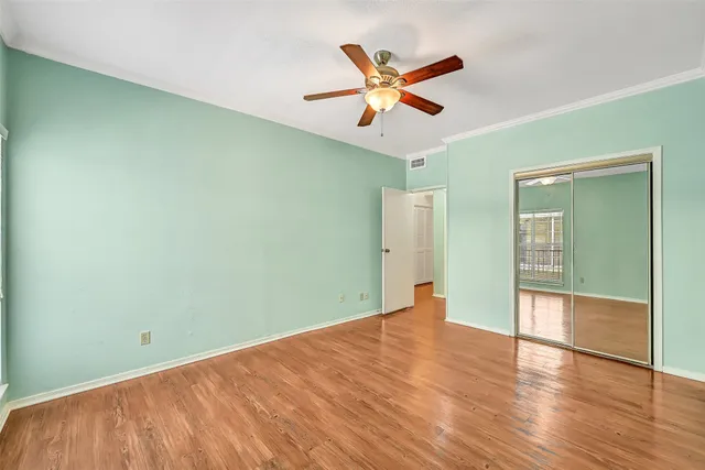 an empty room with wooden floor fan and windows