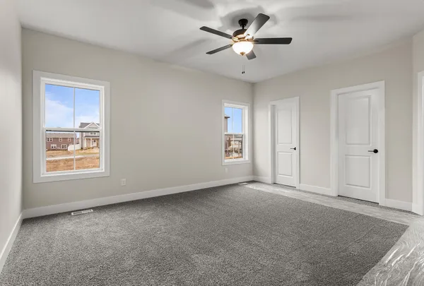 an empty room with a chandelier fan and windows